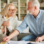 April 25 Events Page Image - The Magnolia at Oxford Commons Elderly man and his wife smiling and holding small dog