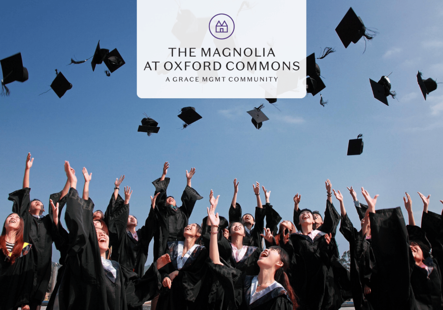 Group of graduates in gowns tossing mortarboards in the air during a sunny outdoor ceremony, with a white logo banner above.